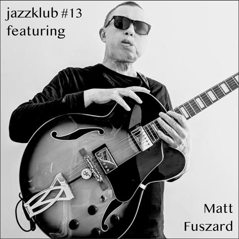 Ein Schwarz-Weiß-Foto eines Gitarristen, mit kurzen Haaren und einem dunklen Pullover, der eine Sonnenbrille trägt und seine Gitarre umgehängt hat und mit beiden Händen hält. 
Oben links steht: "jazzklub #13 featuring" und unten rechts steht "Matt Fuszard" (schwarz auf weiß).