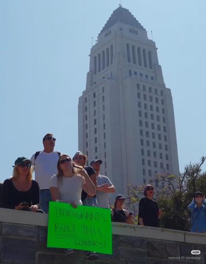 A bunch of protesters, one woman holding a sign that says, "Immigrants built this country."