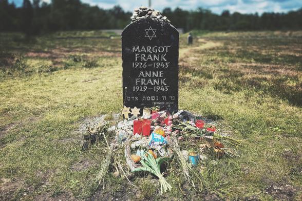 Black memorial stone for Margot and Anne Frank at the former Bergen-Belsen concentration camp. Numerous flowers and candles have been placed in front of the memorial stone.
