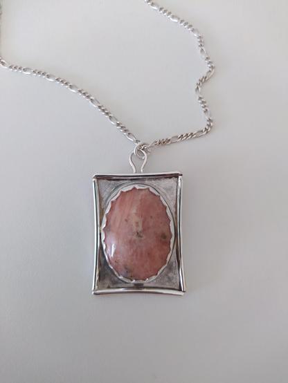 a pendant, it has an oval stone in silver rectangular frame.