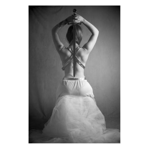 Portrait of a female model facing backwards with a sword across her back.