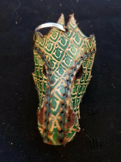 Green leather dragon keychain on a black background. Beware, He is looking at you !