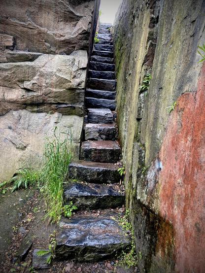 A very narrow path between a rock formation with steps made out of slabs of rock. Location: Kaivopuisto in Helinki, Finland (Suomi).