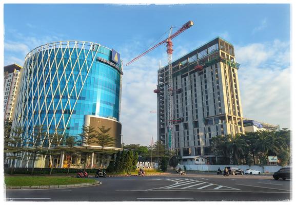 A roundabout with multiple plains, behind it some high rising buildings and a crane.