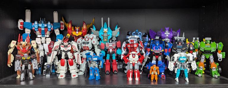 A shelf inside a black cupboard full of Transformers toys.
(L-R) Back: Ultra Magnus, Rodimus, Brainstorm, Whirl, Cyclonus, Sunstreaker.
Middle: Chromedome, Red Alert, Ratchet, Perceptor, First Aid, Skids, Trailbreaker, Hoist
Front: Rewind, Drift, Pipes, Swerve, Rang, Tailgate.