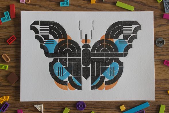 a print of a blue admiral butterfly in black, blue, and orange. it is geometric like the legos it is printed off of