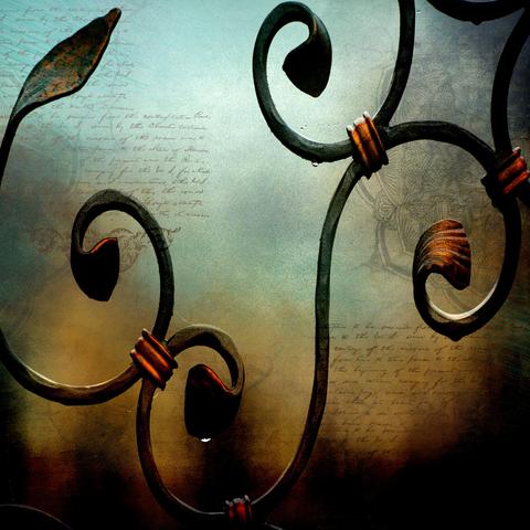 Elegant wrought iron scrollwork with floral and leaf motifs is set against a background of handwritten script. The dark metal curves are accentuated by touches of copper, creating a rich contrast with the soft, blurred backdrop.