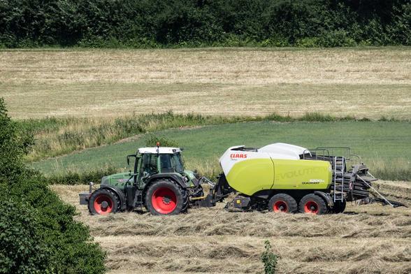 Feld mit Traktor und Heupaketmaschine