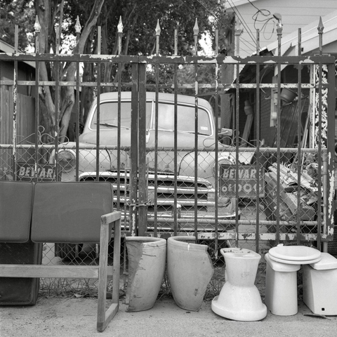 A black and white film photo. A classic Dodge car sits behind a steel gate in Austin Texas. Monday, June 23, 2025.