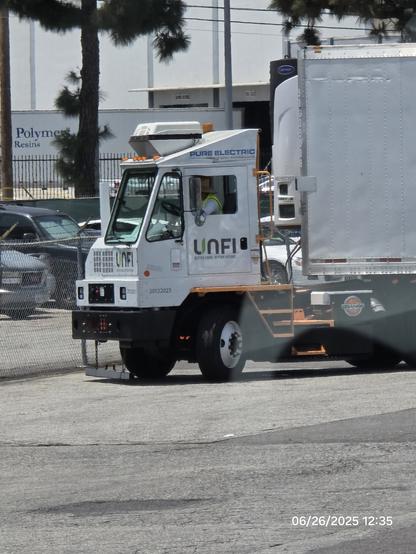 Picture of an electric yard tractor moving a trailer outside a warehouse
