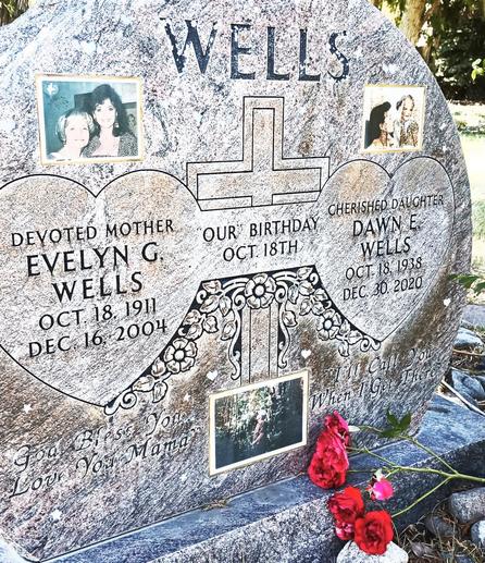 Wells granite gravestone. On the left in a heart carving that says, "Devoted Mother, Evelyn G. Wells, Oct 18, 1911, Dec 16, 2004." A bar connects the heart on the left with one on the right. In the bar it says, "Our Birthday, Oct 18th." In the heart on the right it says, "Cherished Daughter, Dawn E. Wells, Oct 18, 1938, Dec 30, 2020." Under the heart on the left it says, "God Bless You, Love You Mama." Under the heart on the right it says, "I will call you when I get there." There are three photos inset on the gravestone of the two people buried in the plot. Notably, Dawn Wells was an actress best know for playing Mary Ann Summers in the sitcom Gilligan's Island. She was born in Reno, went to Reno High School, and was crowned Miss Nevada in 1959. She was in a couple of movies, a guest star in numerous TV shows, and did some theater work. Wells was involved in numerous humanitarian organizations. She died in 2020 of complications due to COVID.