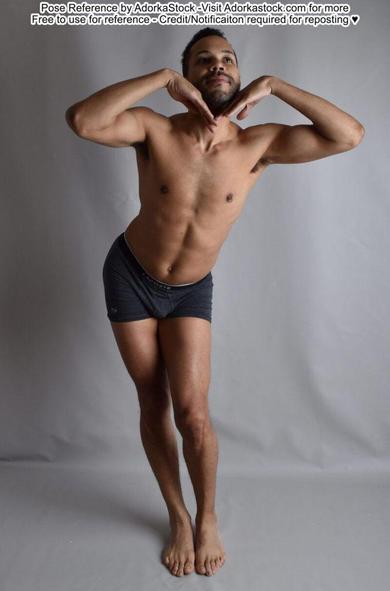 A dark skinned latino man standing contrapposto, hands against his chin as he looks up towards the right.