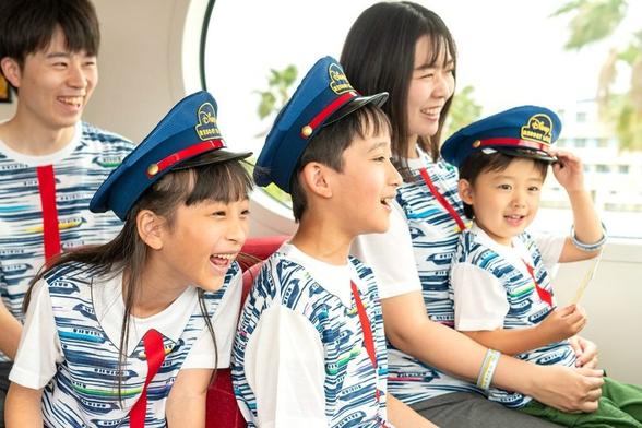 A smiling family in matching shirts and blue hats enjoys a Limited-Time Private Monorail Experience at Tokyo Disney Resort.