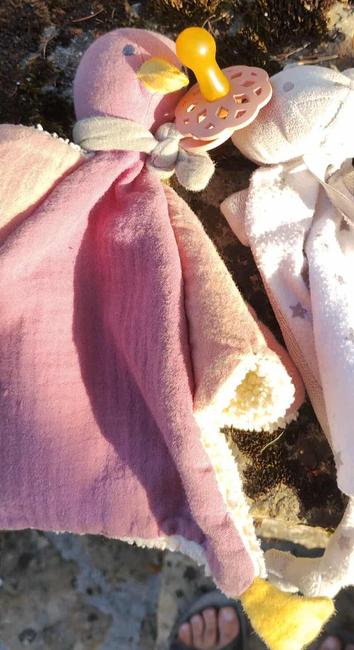 Une peluche canard rose avec une tétine accrochée.