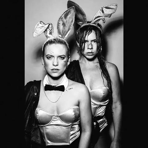 The cover art is largely a black and white photo of the band, two white women looking at the camera, wearing slightly torn/dishevelled Playboy Bunny outfits (i.e., strapless corset/swimsuit things plus bunny ears on their heads) but with a leather jacket hanging from each of their right shoulders, both looking like they've been in a fight. There is a black border on either side of the photo, but no words.