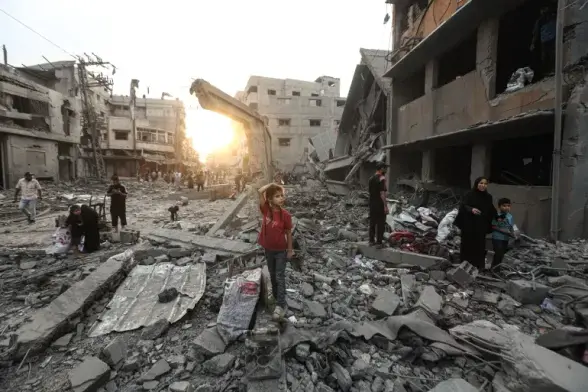 A girl stands in the midst of the rubble.
