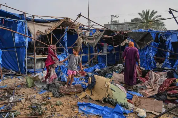A woman and a girl amongst torn tents in hospital courtyard.