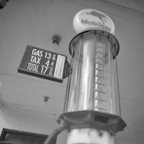 A black and white film photo. An antique gas pump displays the cost of gas, which was 17 8/10 cents per gallon, at a very old gas station in Smithville, Texas. Sunday, June 29, 2025.