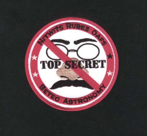 NITWITS RUBES OAFS SETEC ASTRONOMY TOP SECRET badge with a fake nose mustache and glasses disguise on it.