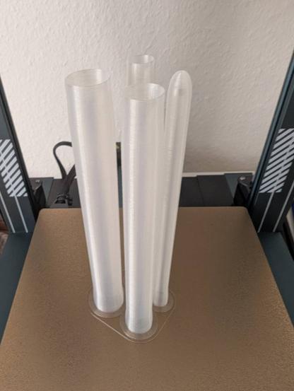 Four tubes printed from transparent PLA on the print bed.