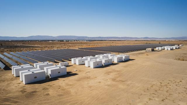Image of a solar plant next to clusters of large white cabinets.