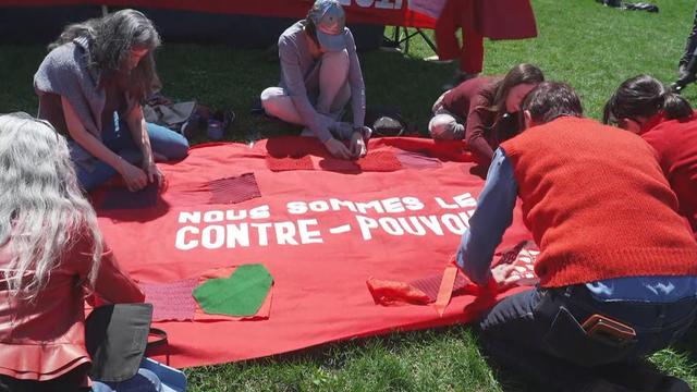 Des gens s'activent autour d'une banderoles rouge qui indique « Nous sommes le contre-pouvoir ».