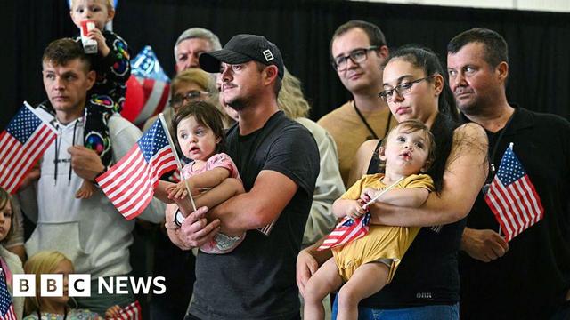 People hold babies and wave American flags