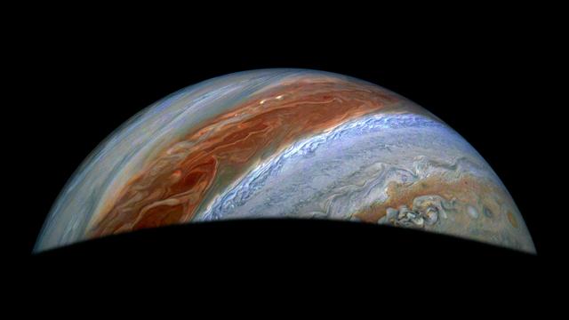 Part of Jupiter is visible in this image. Its iconic belts and zones stand out in rusty red and blue, along with turbulent activity on their edges.
