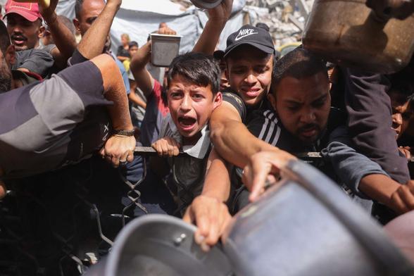 Palestinians try to get a portion of cooked food from a charity kitchen in Jabalia in the northern Gaza Strip on May 17, 2025. The humanitarian crisis in the besieged Gaza Strip has worsened significantly since Israel blocked all aid from entering the territory on March 2, days before resuming its military offensive following a brief ceasefire.