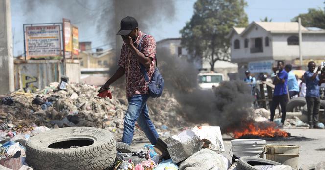 A man walks past a burning barricade set up to protest a lack of security, in the Tabarre neighborhood of Port-au-Prince in February.