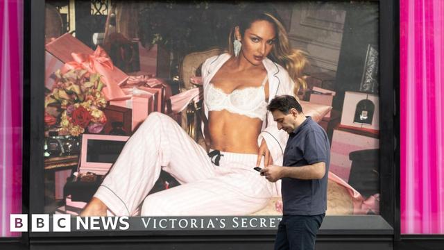 A man walks in front of a Victoria's Secret store front