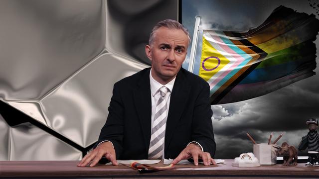 Jan Böhmermann sitzt am Schreibtisch. Rechts neben ihm ist eine Pride-Flagge abgebildet, die verschiedene queere Symbole vereint. Die Ränder der Flagge wirken beschädigt oder verbrannt.