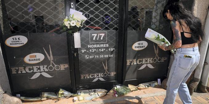 A women lays flowers in front of the hair salon where the murder victim worked, in Puget-sur-Argens, southern France, on 2 June 2025. | PHOTO ABJ/PHOTOPQR/NICE MATIN/MAXPPP