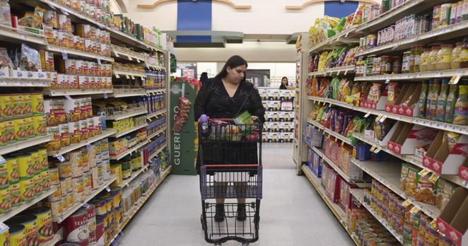Jaqueline Benitez pushes her cart down an aisle as she shops for groceries at a supermarket.
