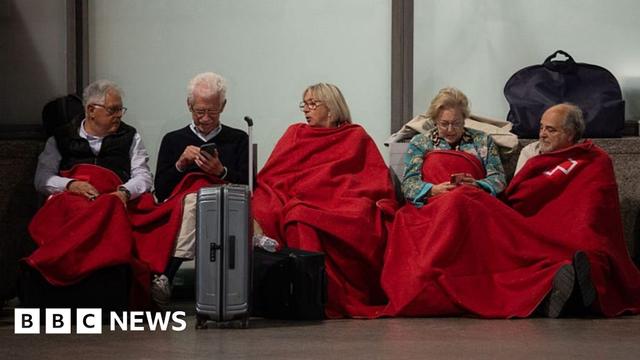 People sit waiting at a Spanish station for the power to come back on in April 2025