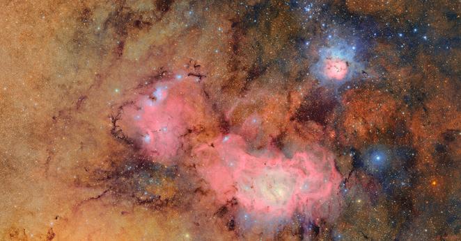 In this image of the Trifid and Lagoon nebulas, clouds of hydrogen emit a pink glow while hot stars shine blue.