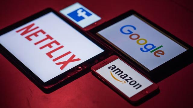 Logo ng Facebook, Netflix, Googlr at Amazon sa mga screen ng smartphones at iPad.