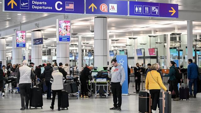 Des voyageurs aux comptoirs d'un aéroport.