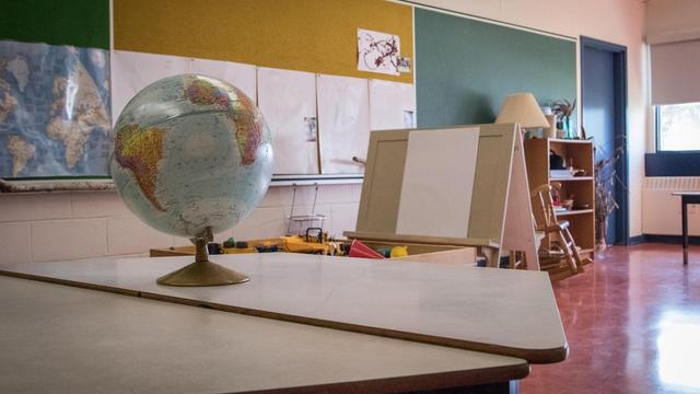 Une classe vide avec un globe terrestre sur un pupitre.