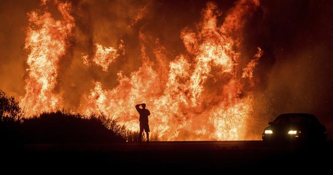 A motorists on Highway 101 watches flames from the Thomas fire leap above the roadway north of Ventura, Calif., on Dec. 6, 2017. Southern California Edison has reached an agreement with state regulators on Thursday, Dec. 16 2021, for more than half a billion dollars in penalties related to five wildfires, including the Thomas fire. 