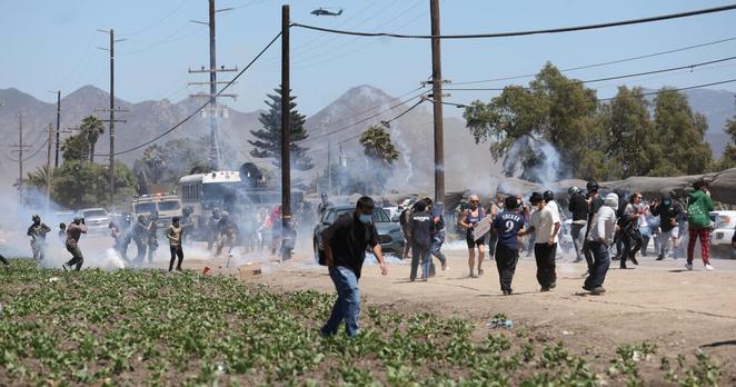 Cabrillo, CA - July 10: Federal officers hold a line as tear gas sends protesters running along Laguna Road on Thursday, July 10, 2025 in Cabrillo, CA. (Julie Leopo / For The Times)