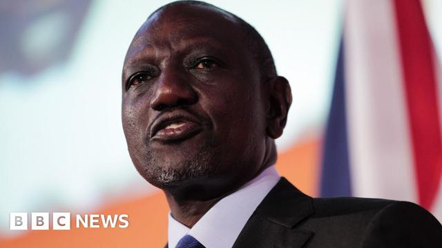 William Ruto, in a black suit, white shirt and blue tie