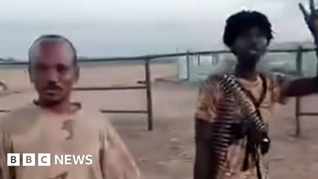 A screengrab of two RSF fighters in el-Fasher's cattle market - one with a belt of ammunition around his neck holds up a victory sign