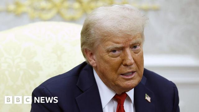 Donald Trump in the Oval Office wearing a blue suit and red tie