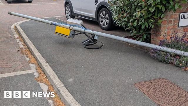 A lamppost, knocked over, with a speed camera attached to it.