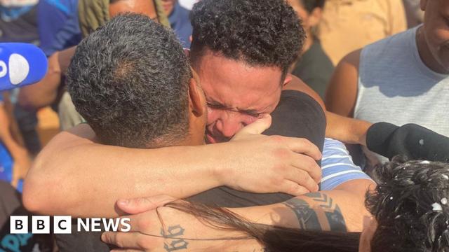 Mervin Yamarte cries as he hugs a relative in the Los Pescadores neighbourhood in Maracaibo. On his arms, he has several tattoos. A microphone can be seen in one corner as journalists try to capture the moment of the reunion