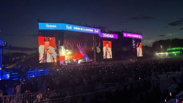 Photo d'une scène et d'écrans géants montrant un chanteur devant une vaste foule.