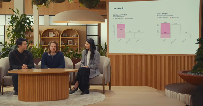 At OpenAI’s office, three people are onstage with a presentation behind them.