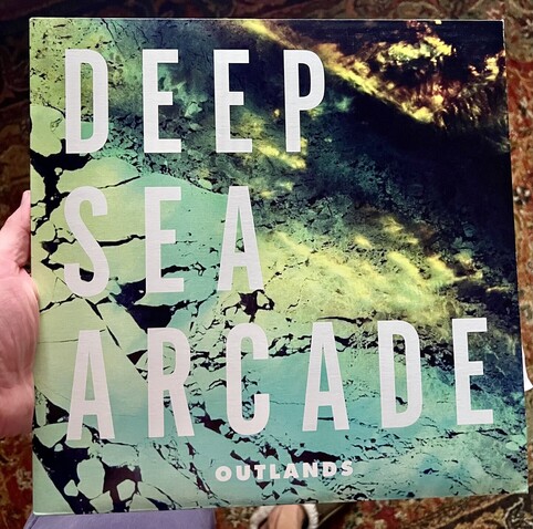 Deep Sea Arcade’s Outlands album cover with abstract background artwork. 